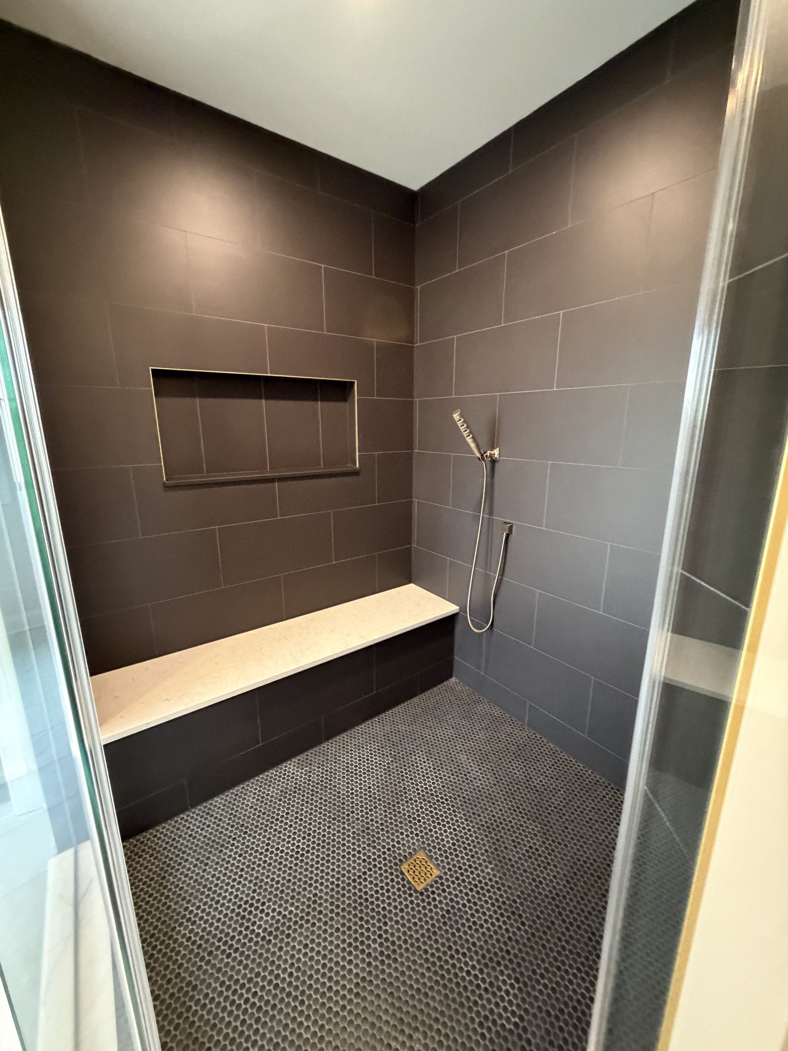 Dark tile shower with bench