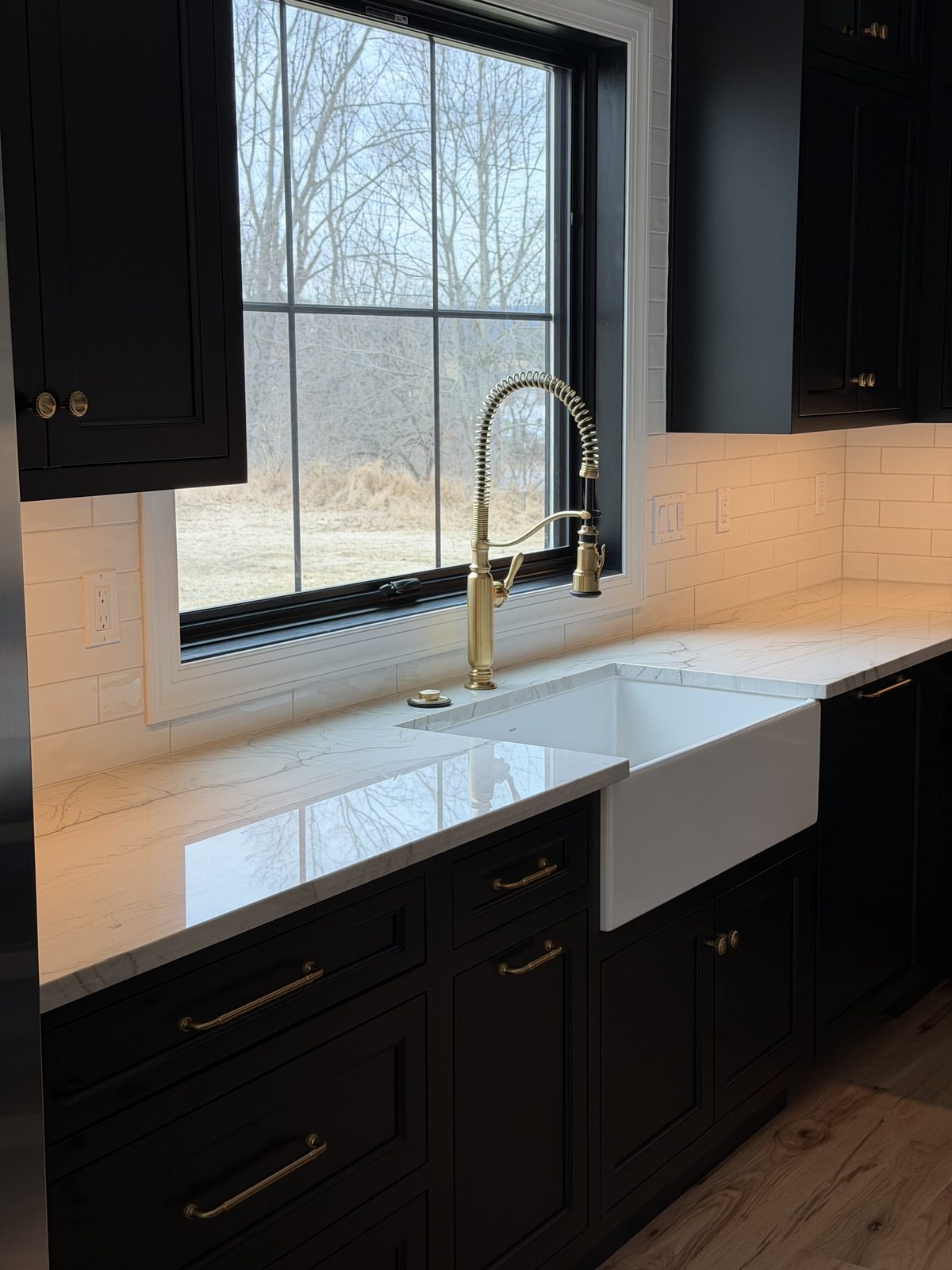 Black cabinet kitchen with farmhouse sink and brass faucet