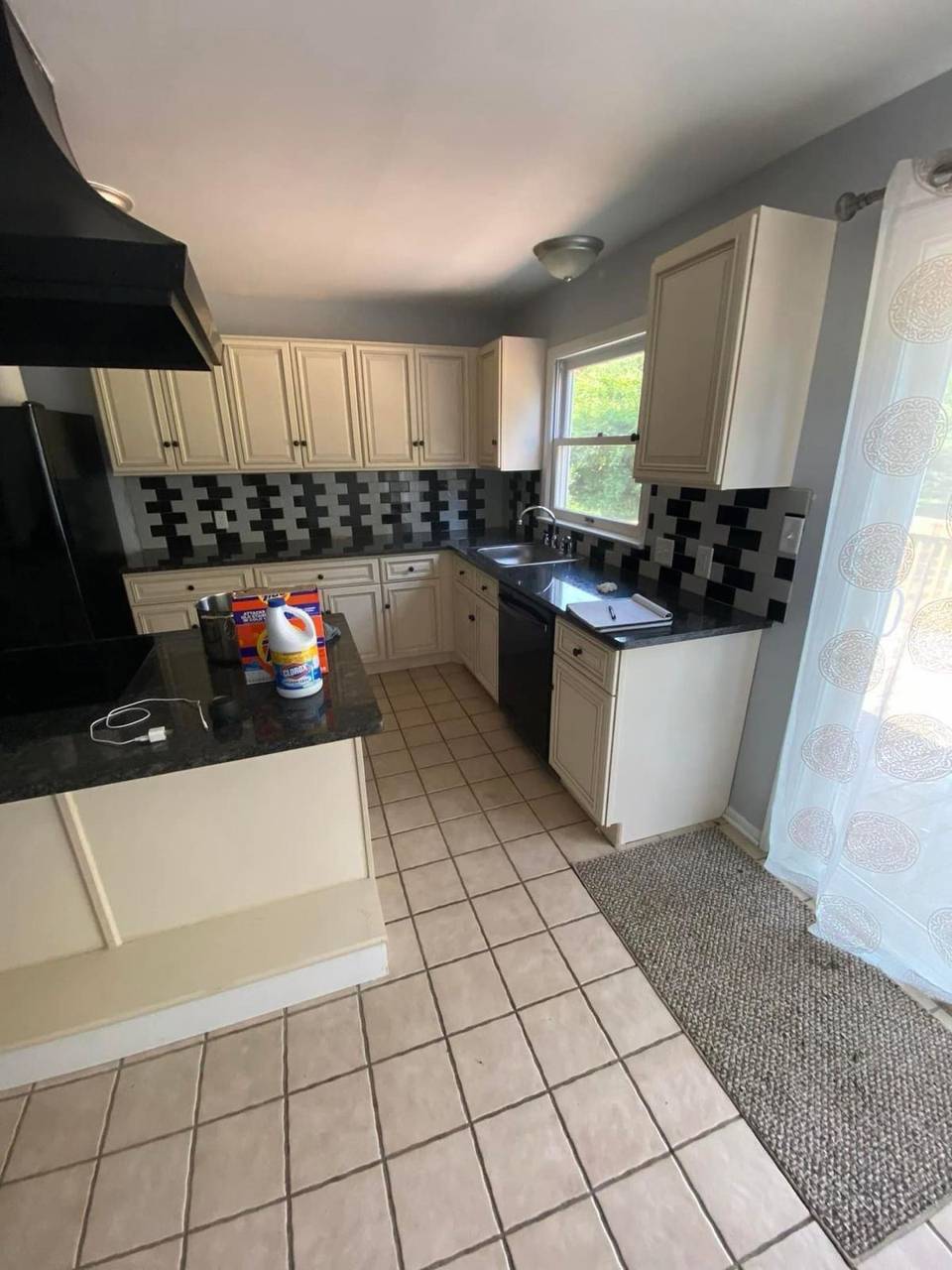 Kitchen before remodel — cream cabinets and black backsplash